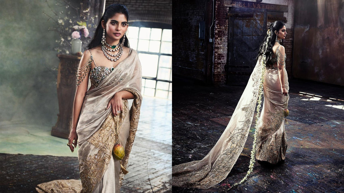 Isha Ambani in a silver sari carrying the hand-crocheted Mango Jaal with Subodh Gupta’s bronze mango sculpture